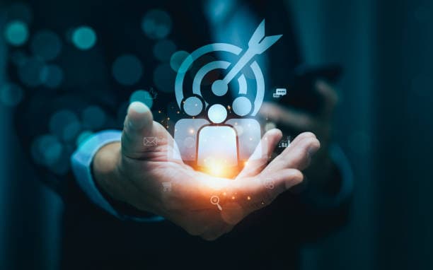 Open hand holding a glowing customer icon beneath a target and arrow